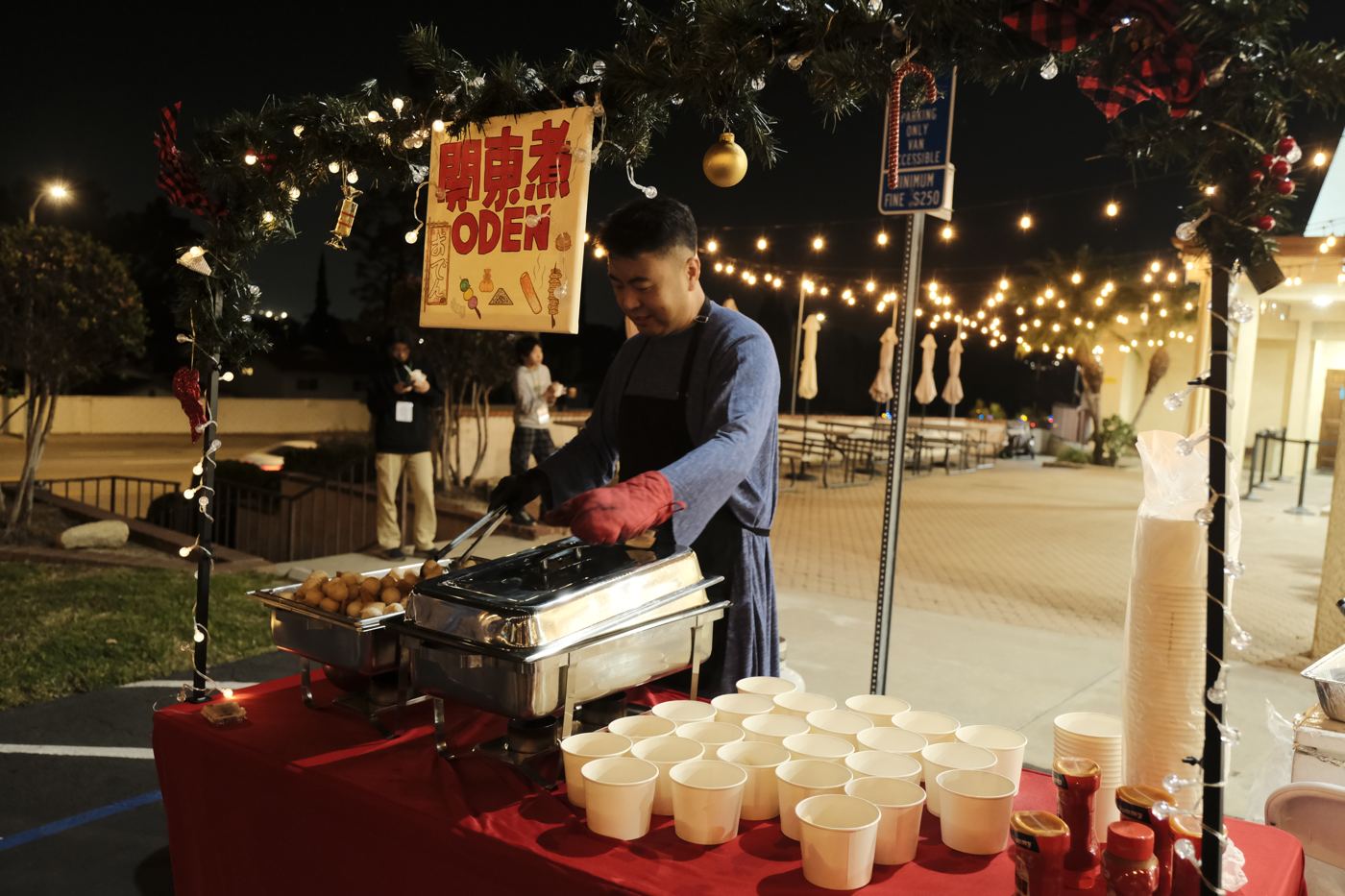 燈串下的小吃攤，弟兄正在準備熱食
